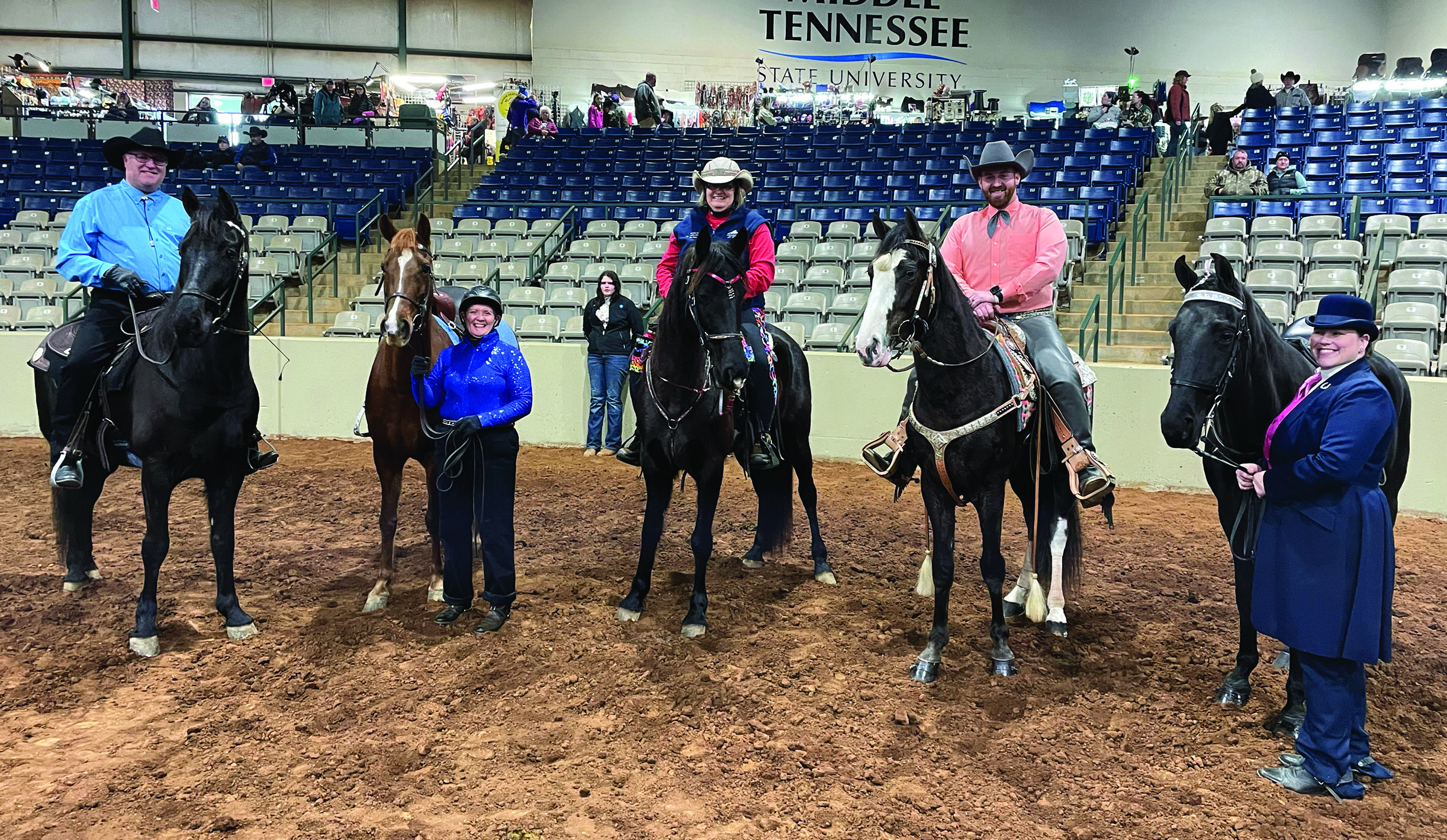 three people on horses and two people standing with their horse